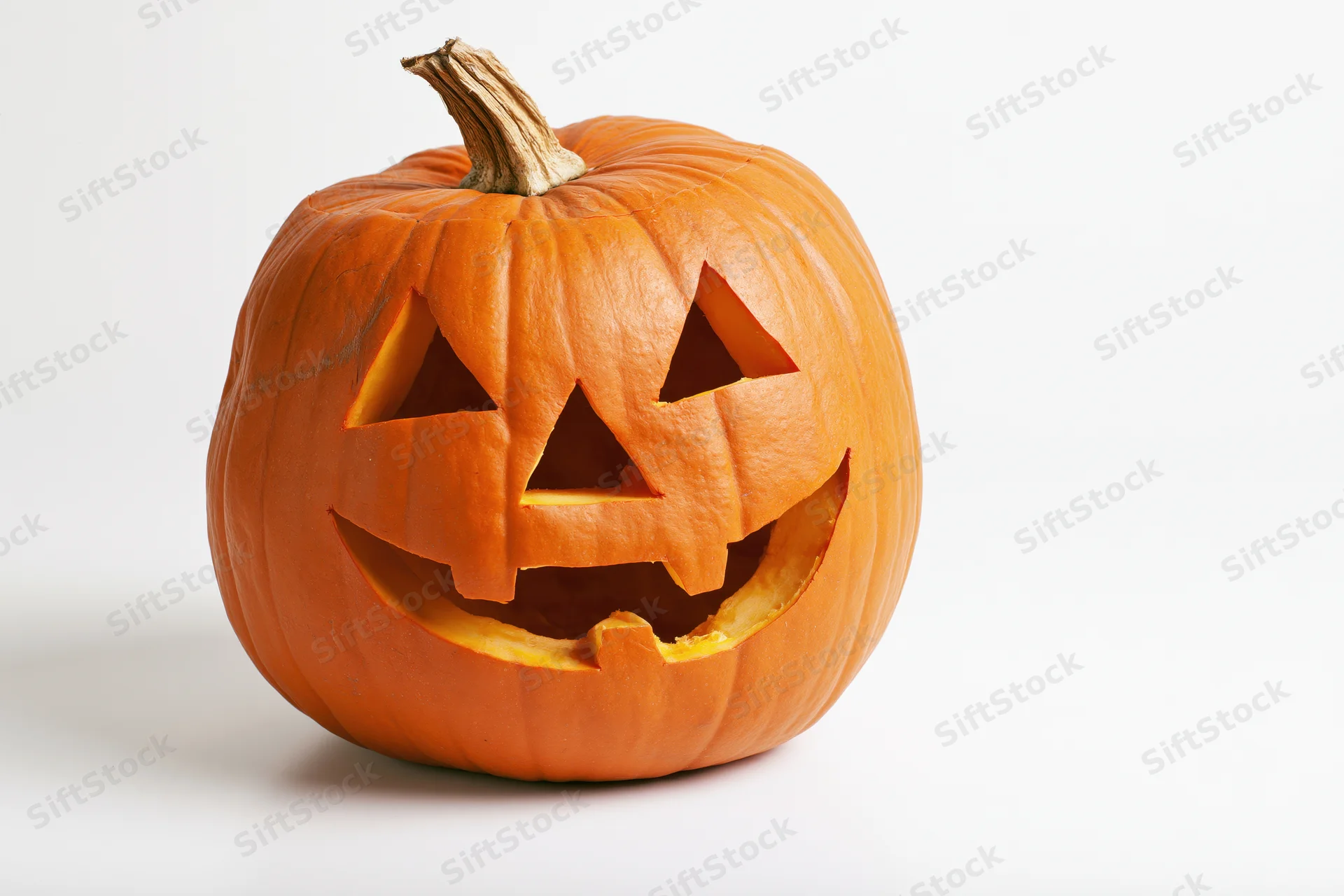 Carved pumpkin with triangular eyes and wide grin on white background