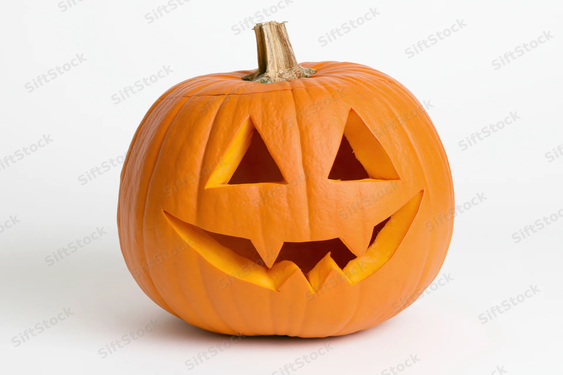 Carved pumpkin with triangular eyes and toothy grin on white background