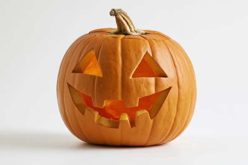 Carved pumpkin with triangular eyes and jagged mouth on white background
