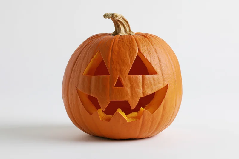 Carved pumpkin with triangular eyes and grin on white background
