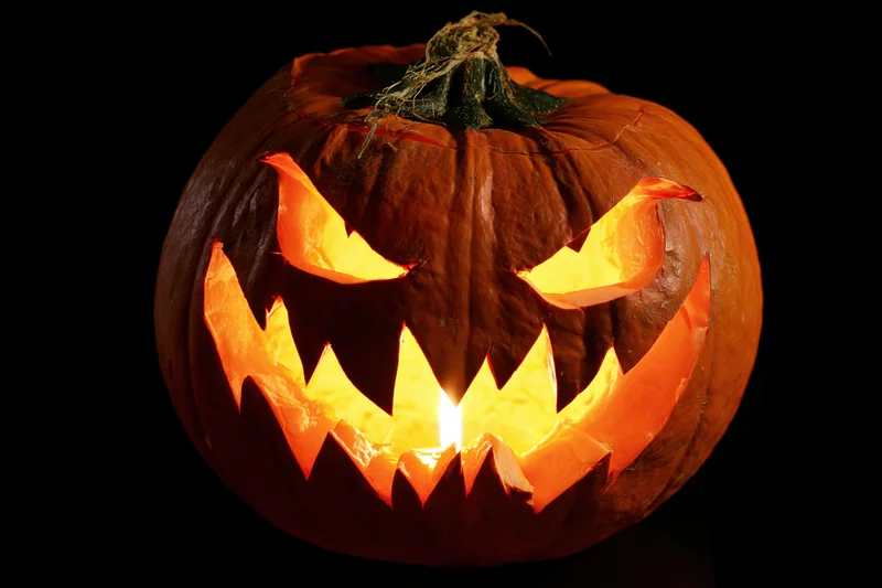 Carved pumpkin with jagged face glowing in darkness