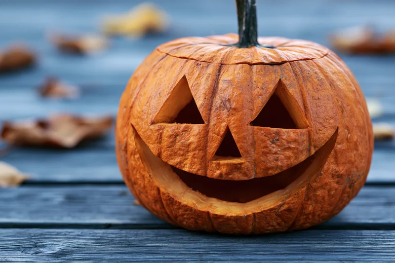 Carved jack-o-lantern with smiling triangular eyes on a dark wooden table
