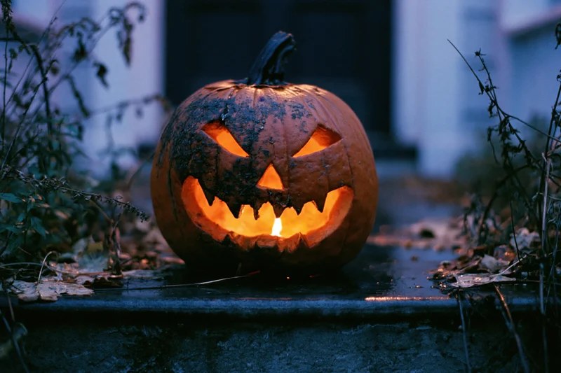 Carved jack-o-lantern glowing with candlelight on a porch step at night