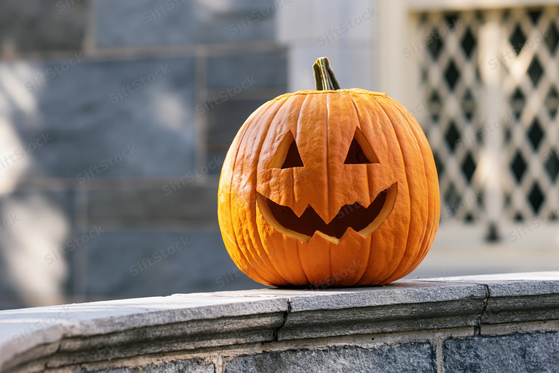 Carved jack-o-lantern pumpkin on stone wall outdoors