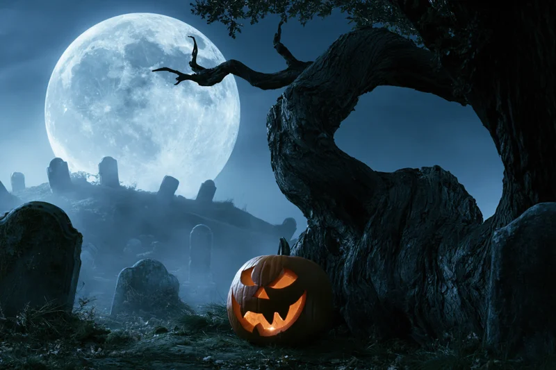 Carved pumpkin glowing in foggy graveyard under full moon near twisted tree
