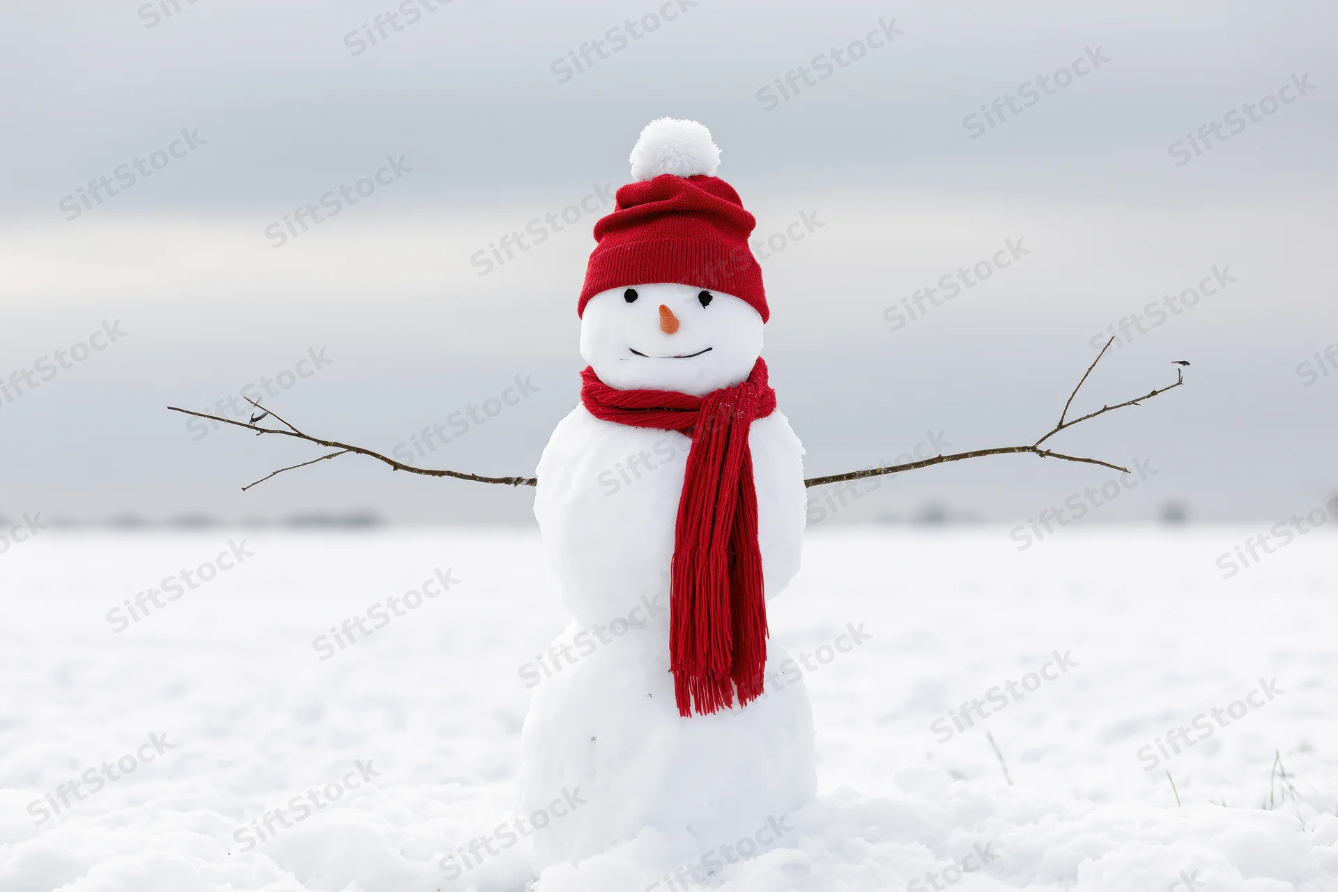 Cheerful snowman with red hat and scarf standing in open snow-covered field