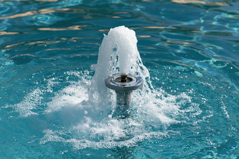 Chrome fountain jet spraying foamy water in a swimming pool
