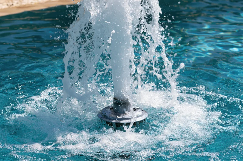 Chrome fountain jet spraying water in a swimming pool