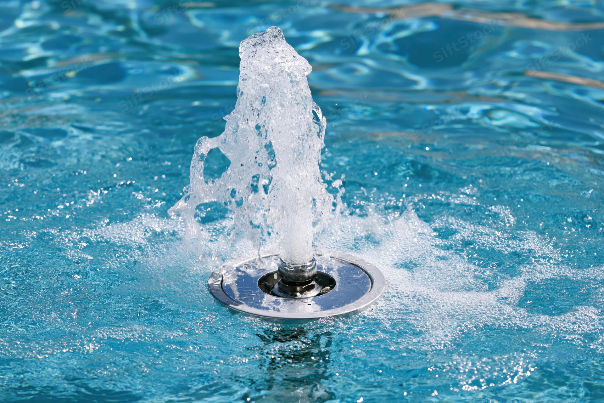 Chrome fountain jet spraying water in a swimming pool