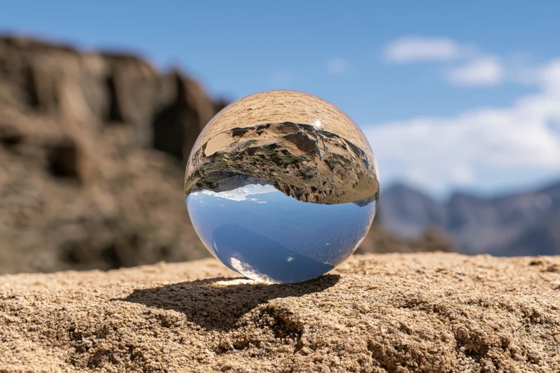Crystal ball resting on a granite rock reflecting desert mountains and sky
