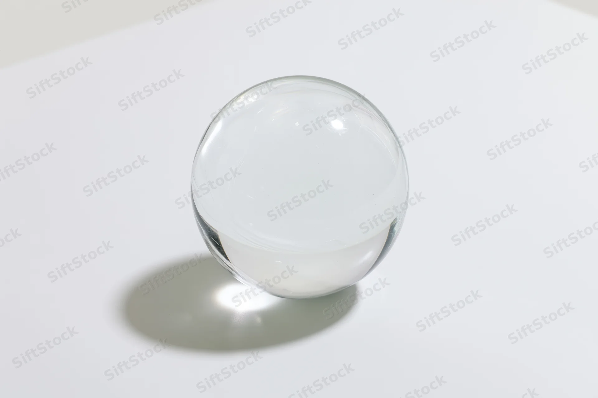 Clear glass sphere resting on a white surface in closeup view