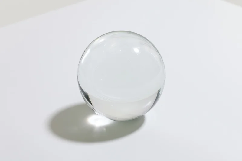 Clear glass sphere resting on a white surface in closeup view