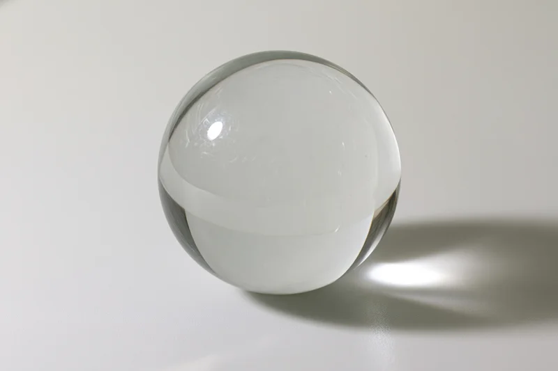 Clear glass sphere resting on white surface in studio lighting