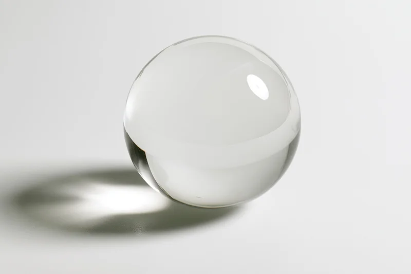 Clear glass sphere resting on white surface in studio lighting