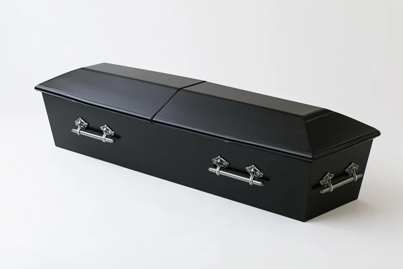 Closed black wooden coffin with silver metal handles on white background