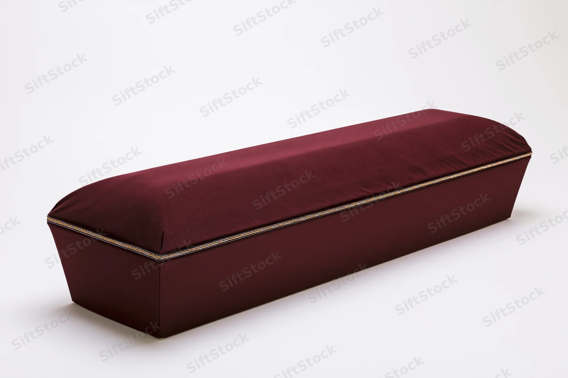 Closed burgundy velvet coffin with gold trim on white background
