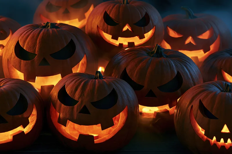 Carved jack-o-lanterns glowing with candlelight in a dark cluster