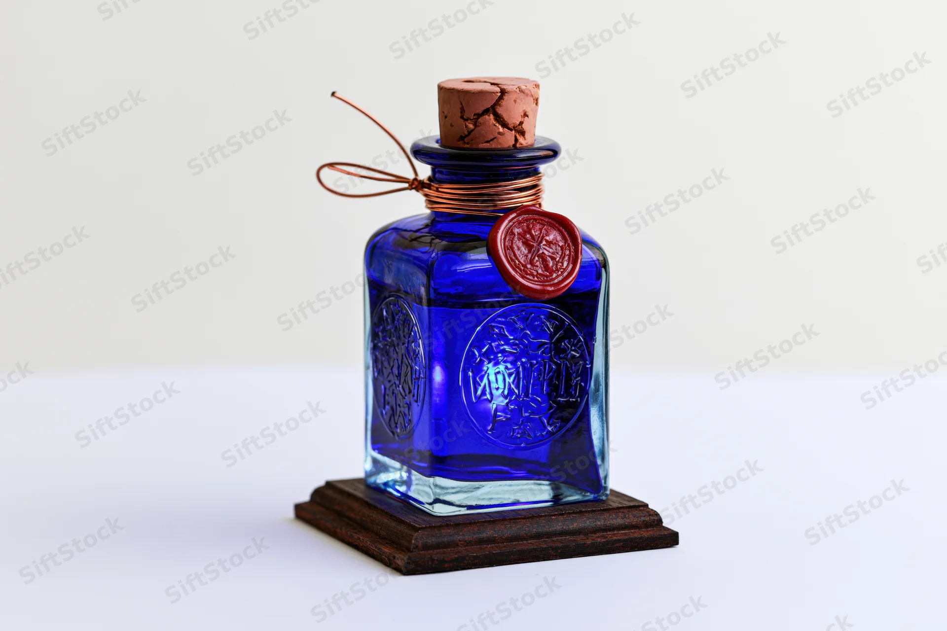 Cobalt blue glass apothecary bottle with embossed runes and red wax seal on wooden base