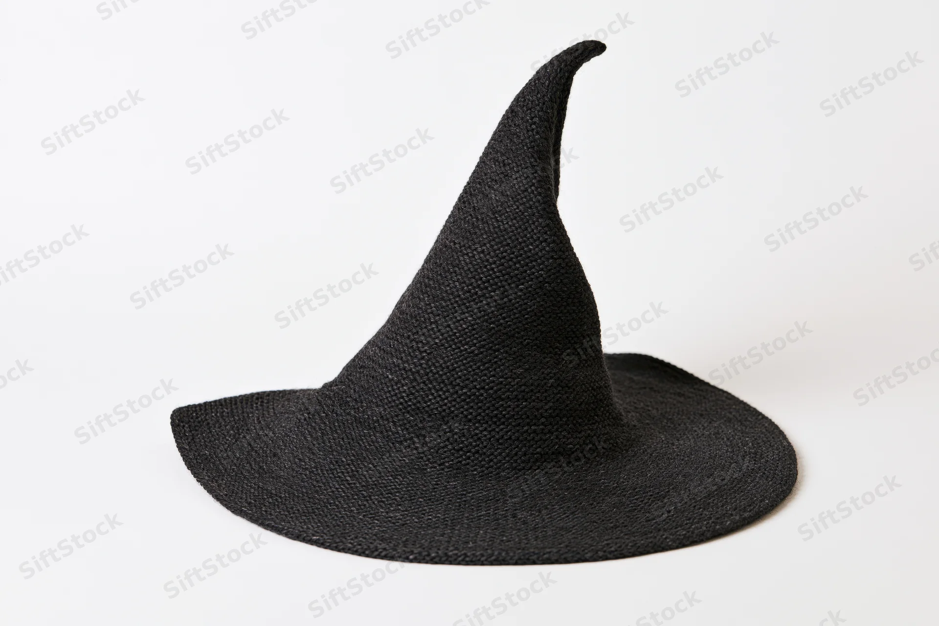 Black knitted witch hat with pointed asymmetric top on white background