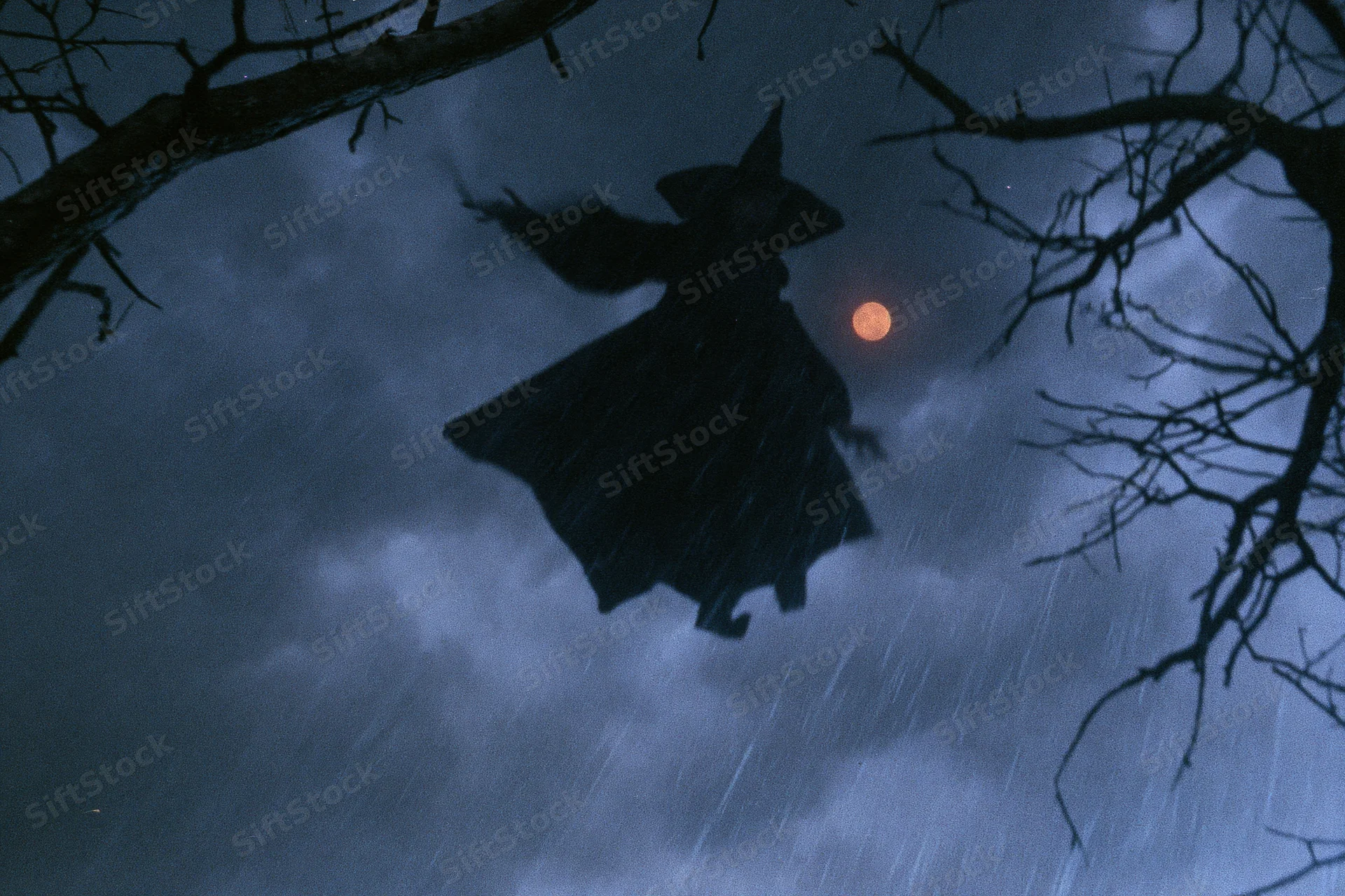 Witch flying on broomstick through stormy night sky with full moon and bare tree branches
