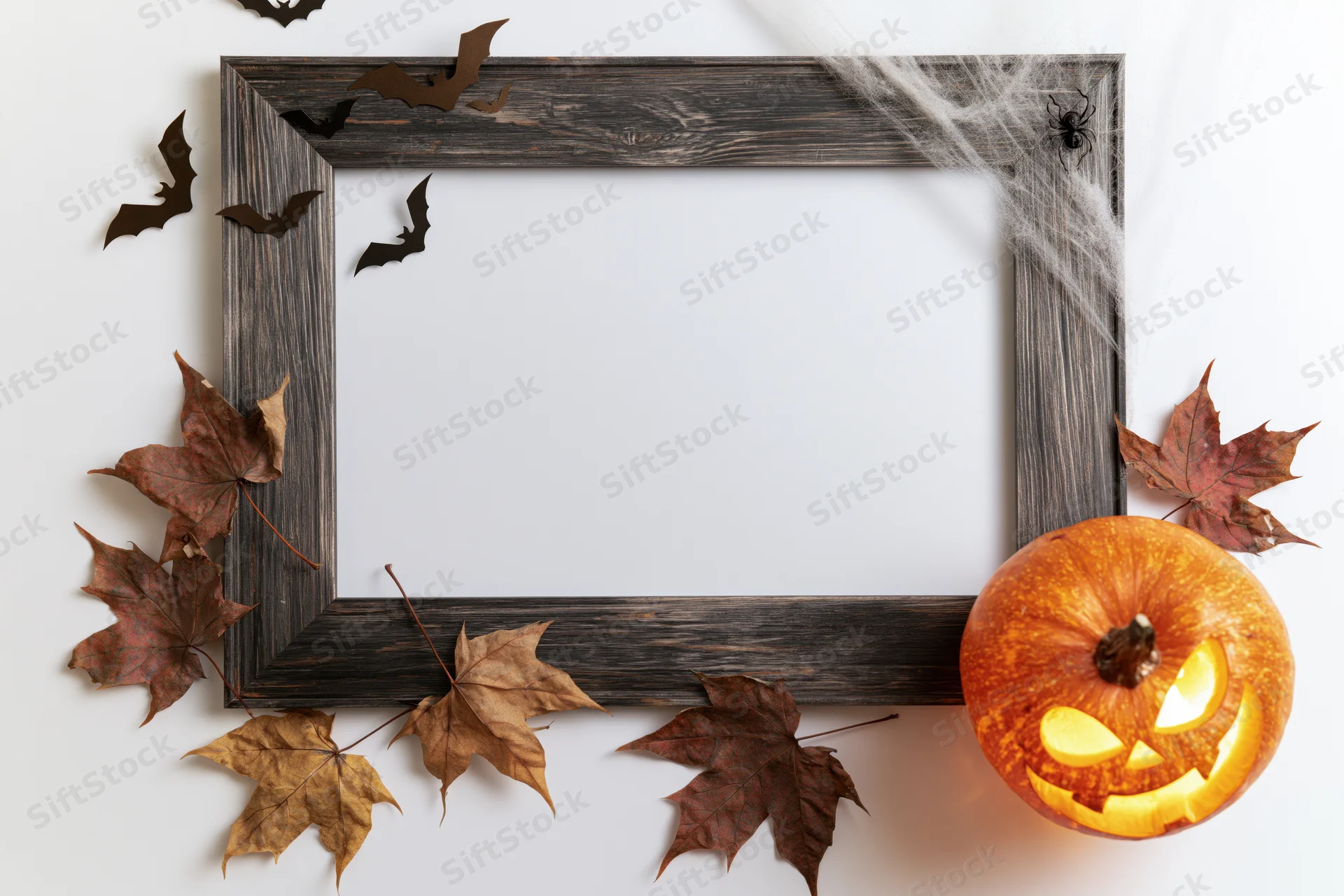 Dark weathered wooden frame decorated with autumn leaves, bats, spiderweb, and glowing jack-o-lantern for halloween display