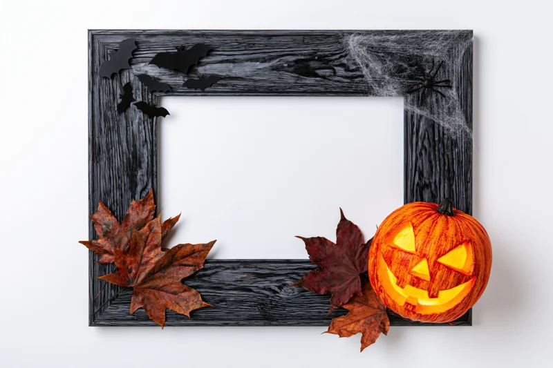 Dark weathered wooden frame decorated with halloween pumpkins, bats, spiderwebs, and autumn leaves, flat lay on white background