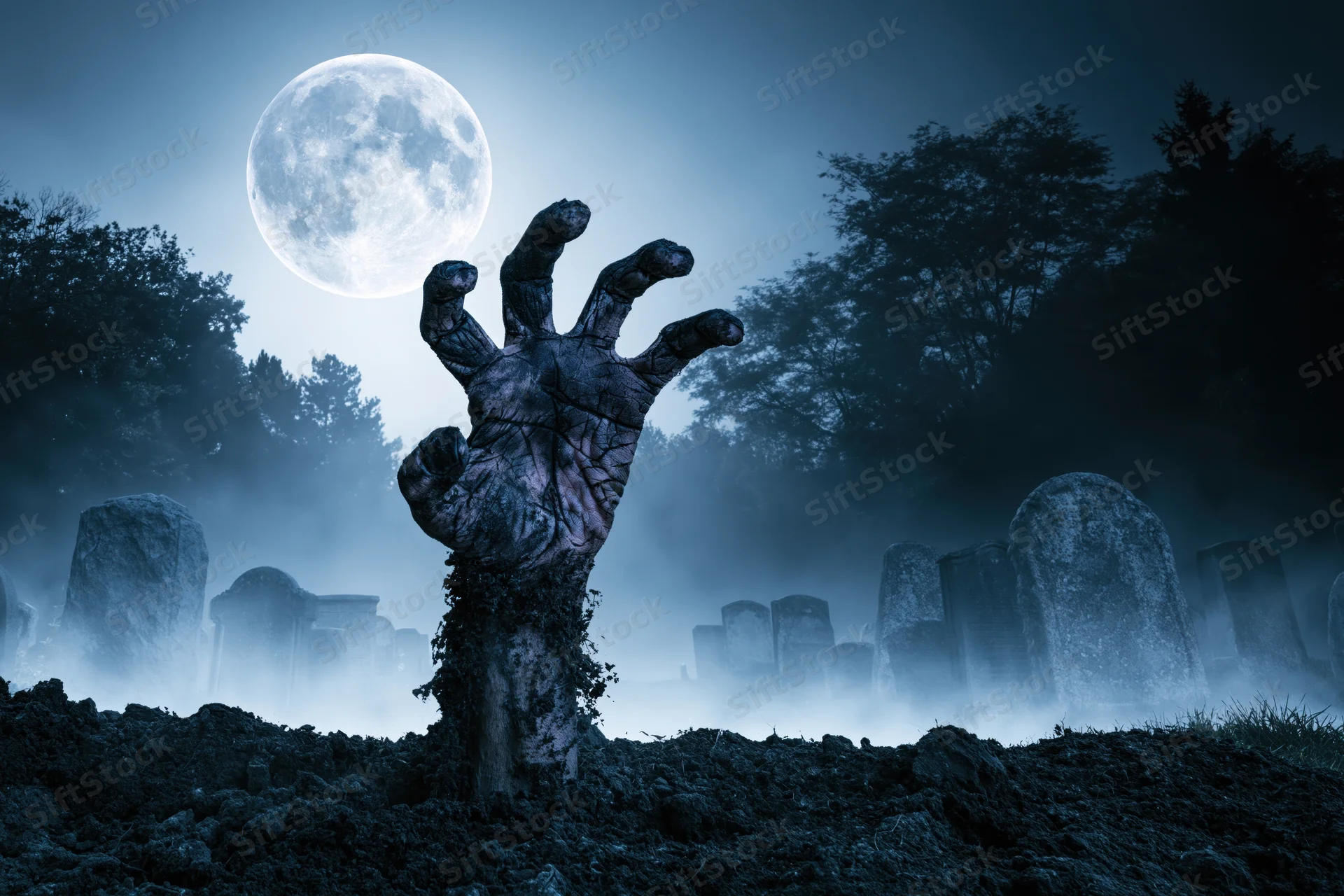 Decayed hand emerging from soil in a foggy graveyard under a full moon