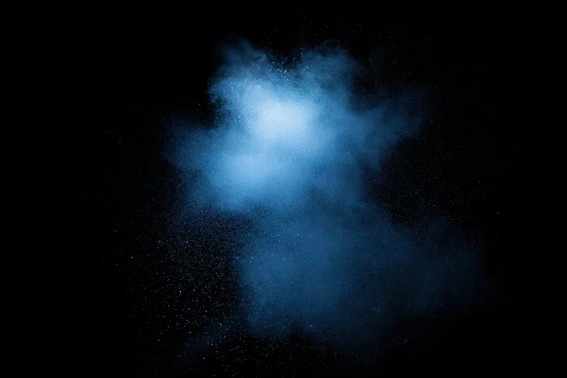 Blue powder cloud suspended mid-air against dark background