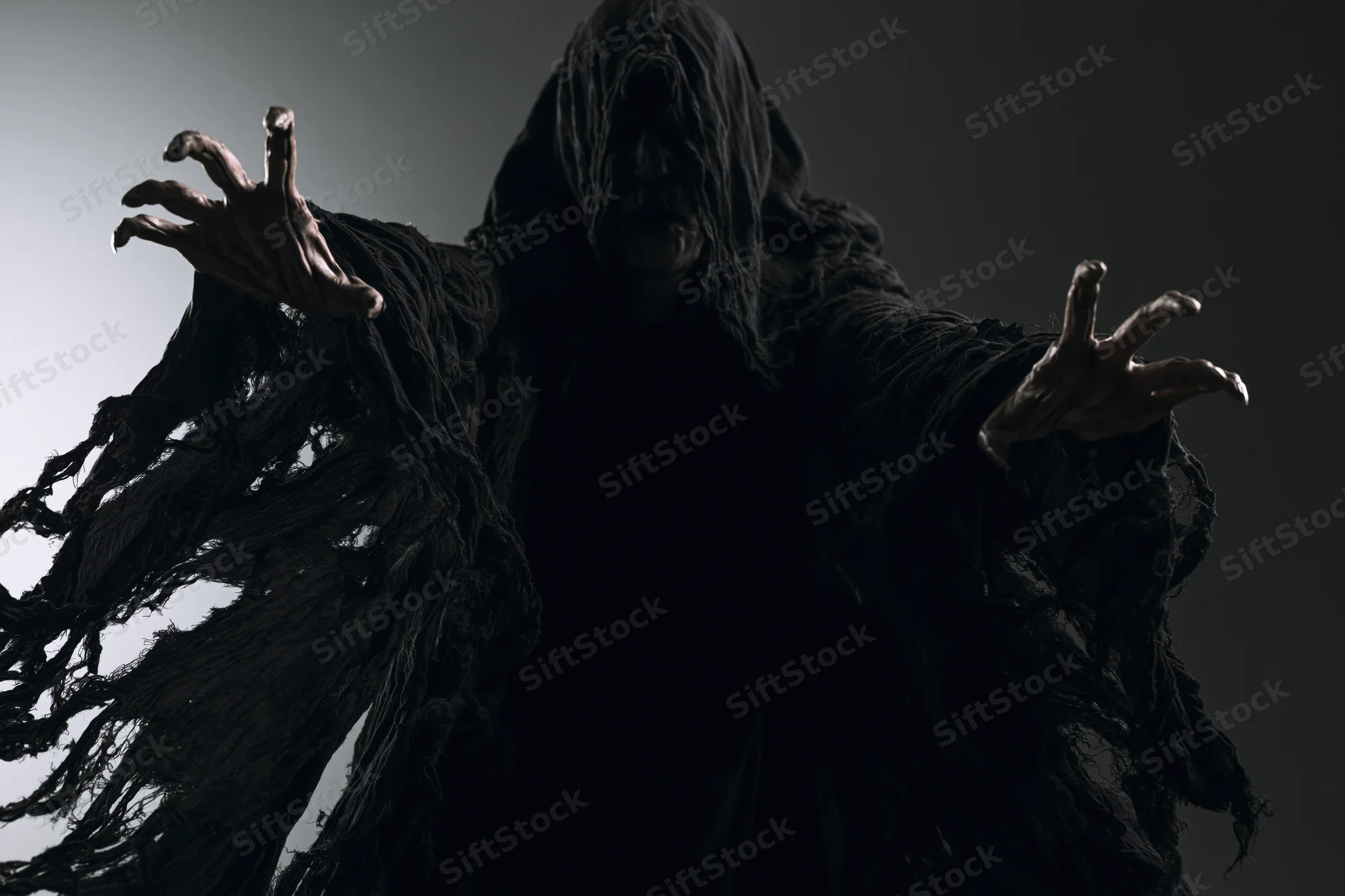 Hooded figure in tattered black robe with outstretched clawed hands against dark background