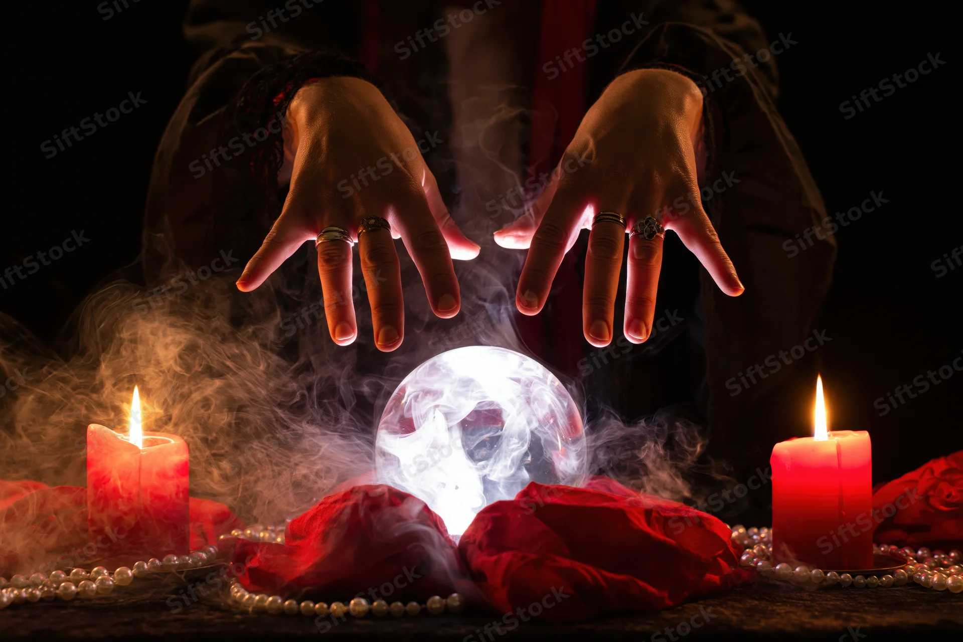 Fortune teller's hands hovering over glowing crystal ball surrounded by candles, smoke, red roses and pearls