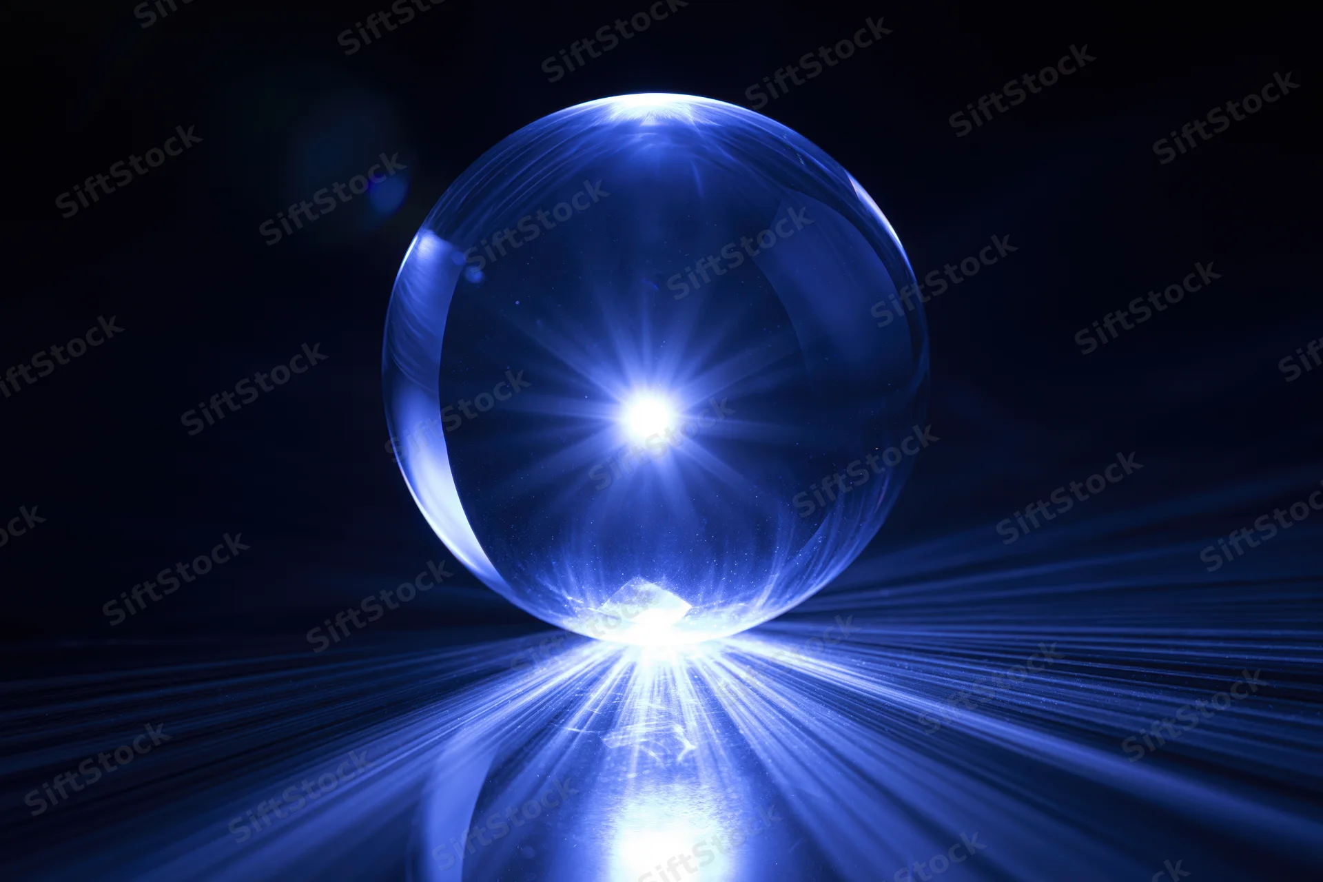 Glowing crystal ball resting on dark reflective surface with radiant light beams