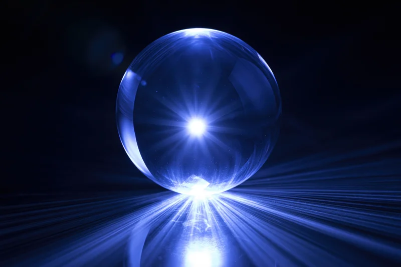 Glowing crystal ball resting on dark reflective surface with radiant light beams