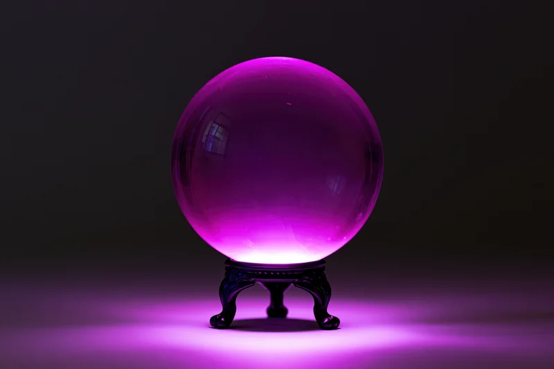 Glowing magenta crystal ball on ornate stand in dark studio setting