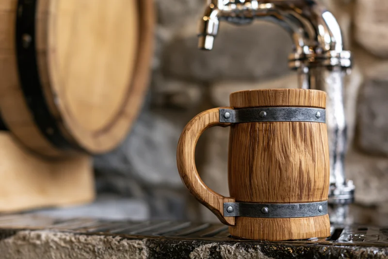 Wooden beer mug with metal bands on stone bar counter near tap