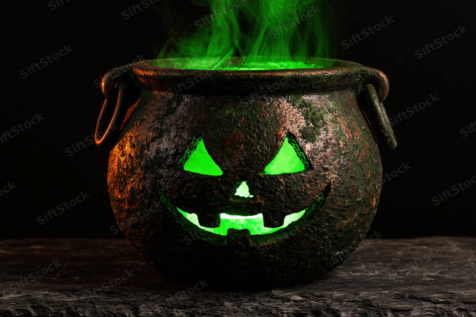 Aged cast iron cauldron with jack-o-lantern face glowing green and emitting smoke on dark stone surface