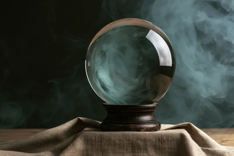 Crystal ball with swirling smoke on wooden stand draped in burlap cloth