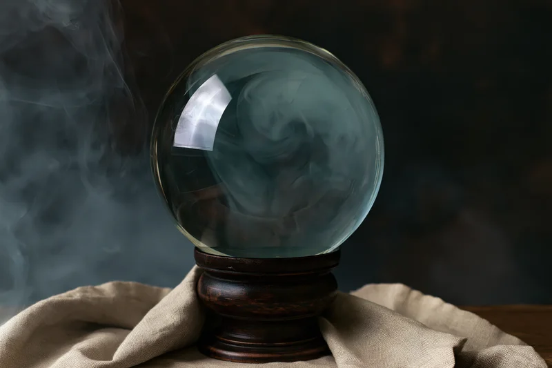 Glass crystal ball with swirling smoke on wooden stand draped in beige cloth