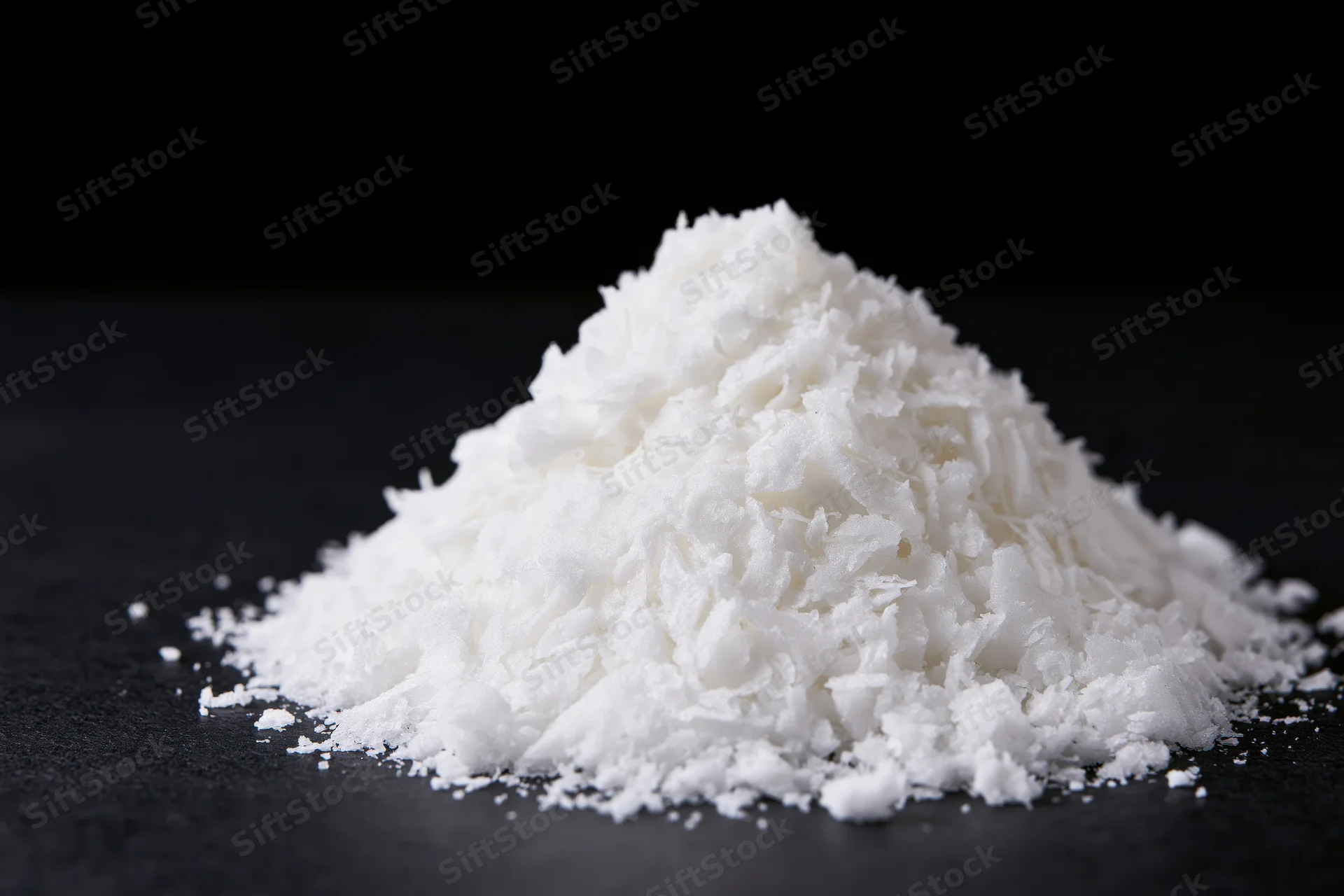 Pile of white shredded coconut on black surface
