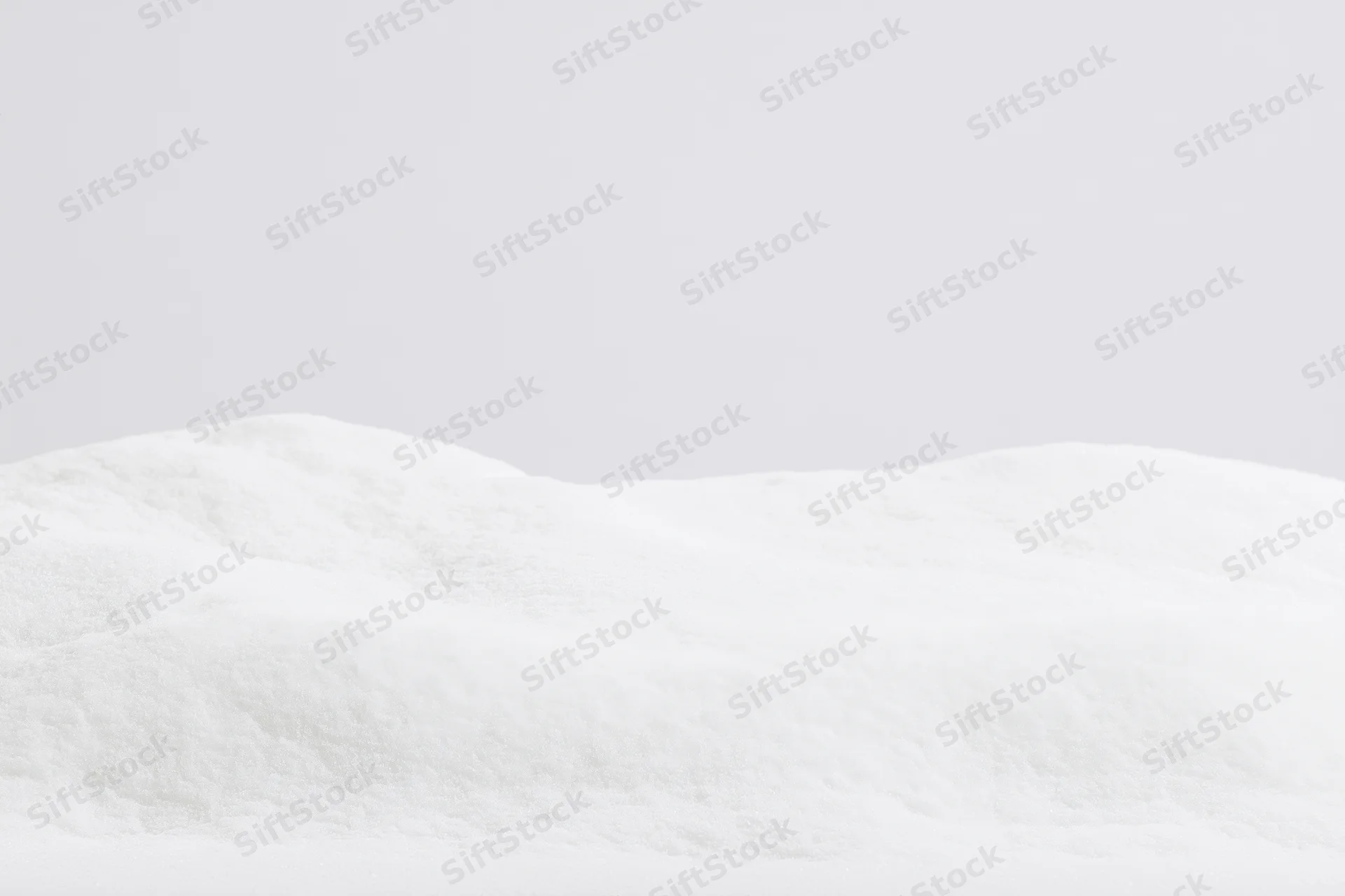 Low mound of fresh white snow filling the bottom third of the frame against a plain white background