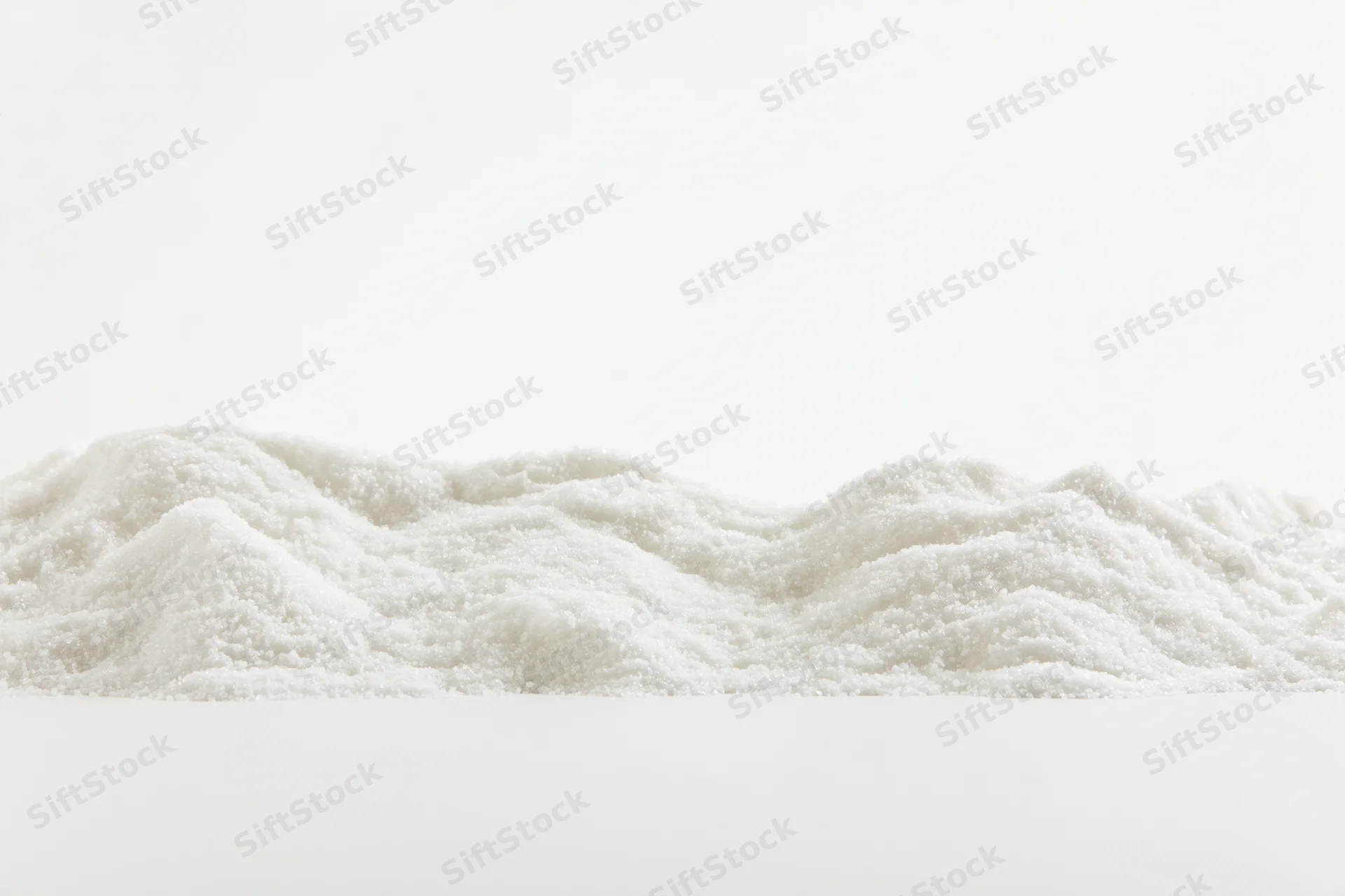 A low ridge of fine white granular powder salt or sugar piled on a plain white surface