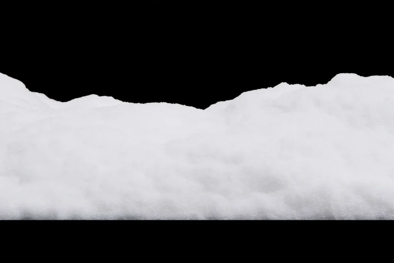 Low ridge of fresh white snow filling the bottom third of the frame against black background