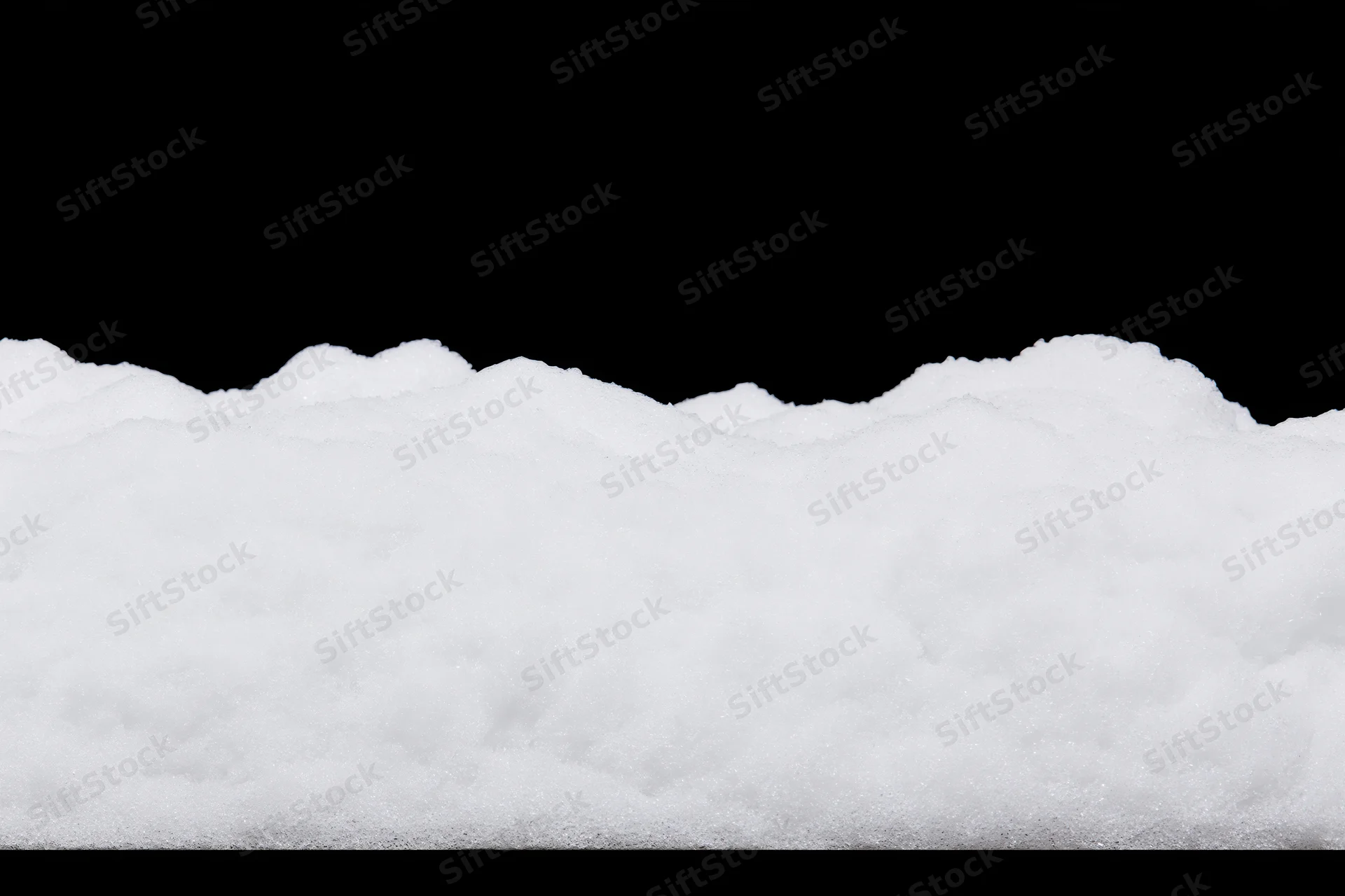 Low ridge of fresh white snow filling the bottom third of the frame against a black background