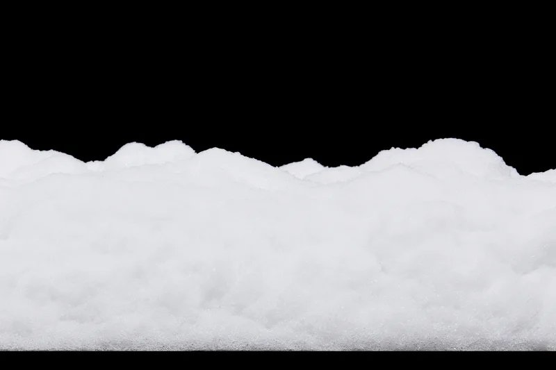 Low ridge of fresh white snow filling the bottom third of the frame against a black background
