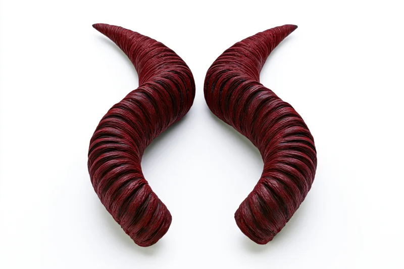 Pair of dark red spiral ridged demon horns on white background