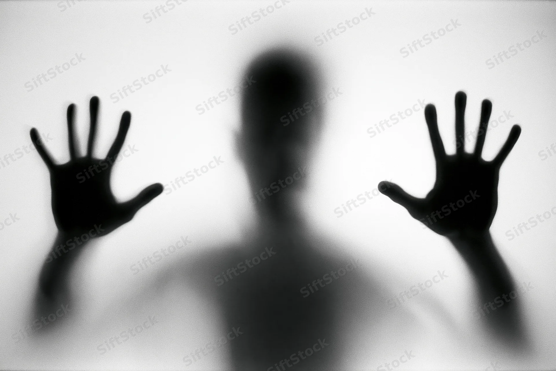 Silhouette of a person pressing hands and face against frosted glass