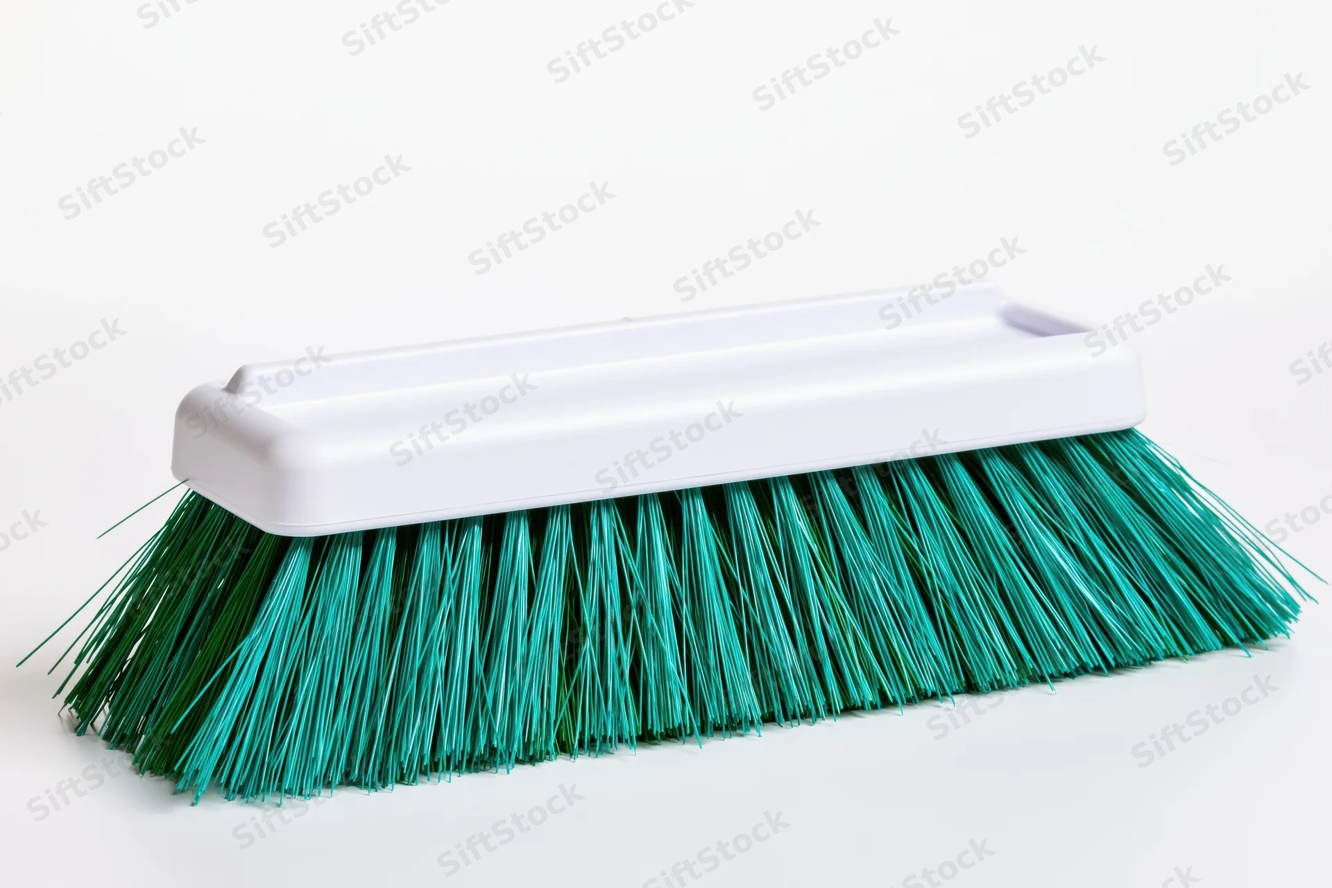 Plastic broom head with teal and green synthetic bristles on white background
