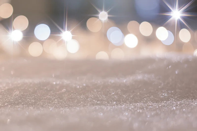 Glittering snow surface with blurred festive lights in background