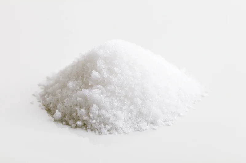 A heap of coarse white salt on a plain white surface