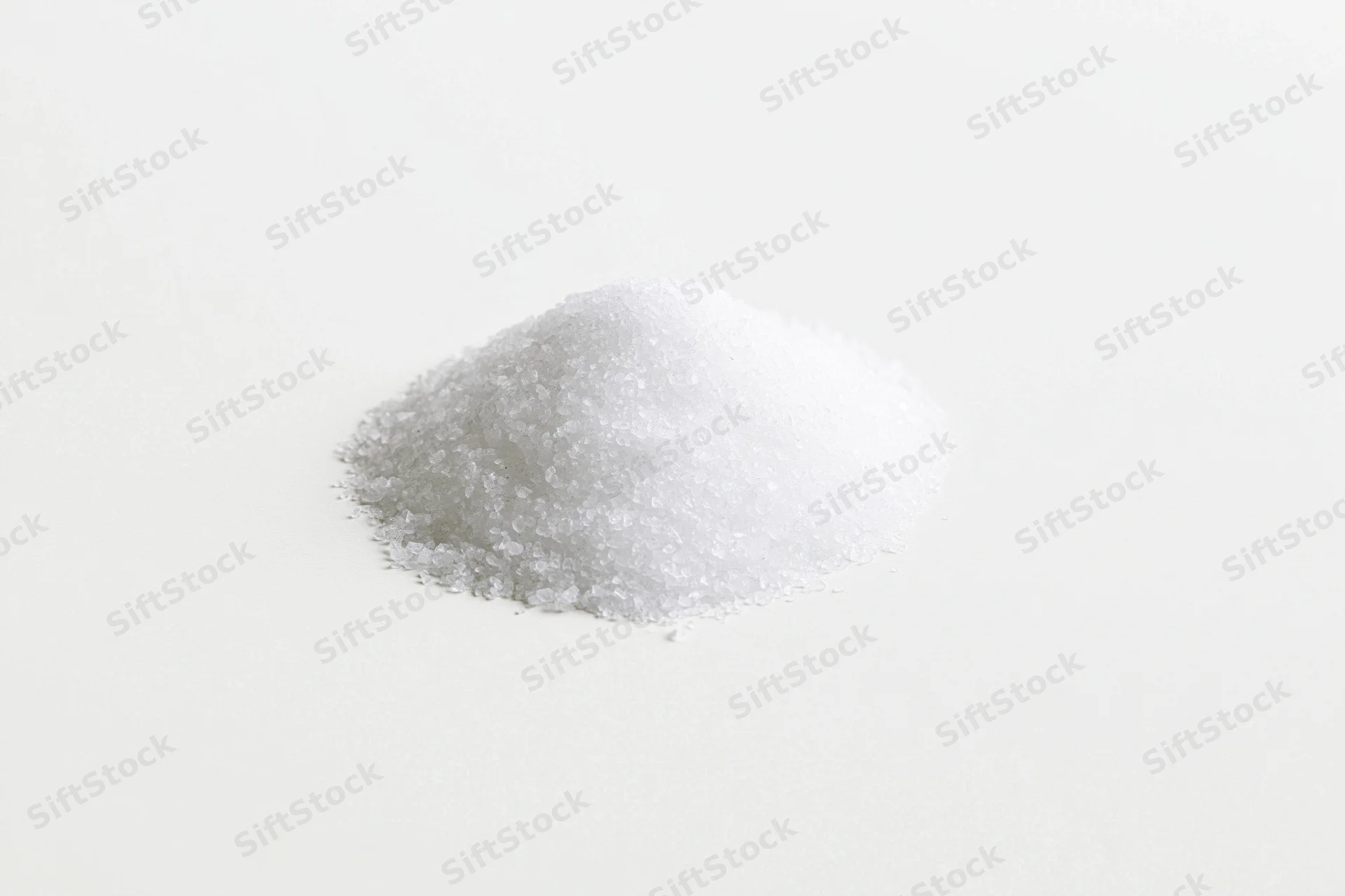 A small pile of coarse white salt on a plain white surface