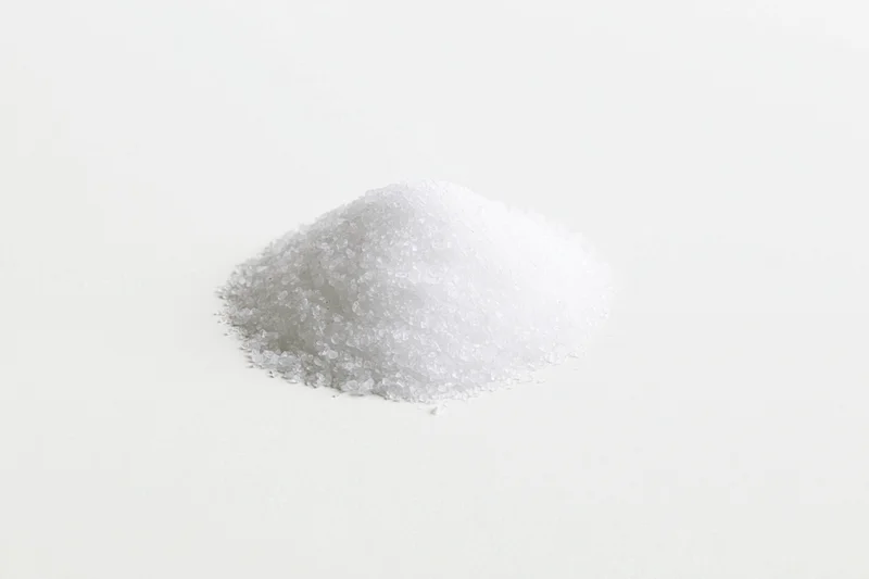 A small pile of coarse white salt on a plain white surface
